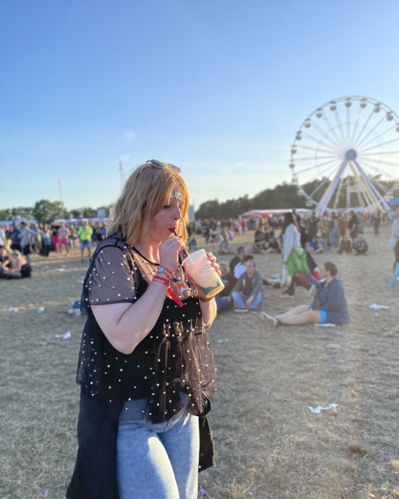 Maren Thiel, Social Media Managerin aus Nordfriesland, mit Getränk auf einem Festivalgelände, im Hintergrund ein Riesenrad